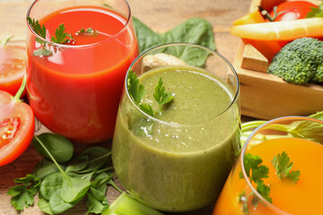 Delicious vegetable juices and fresh ingredients on wooden table, closeup