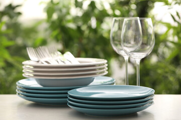 Fototapeta na wymiar Set of clean dishware and wineglasses on white table against blurred background