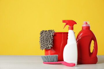 Bucket, cleaning products and tools on grey table. Space for text