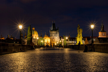 Fototapeta na wymiar old paved sidewalk with paving stones in memory of Charles Bridge from the 14th century in the center of Prague and in the background the old bridge tower at night in the Czech Republic