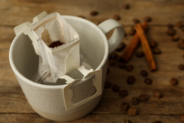 Fototapeta na wymiar Drip coffee in cup on wooden table, closeup