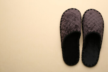 Pair of soft slippers on beige background, flat lay. Space for text