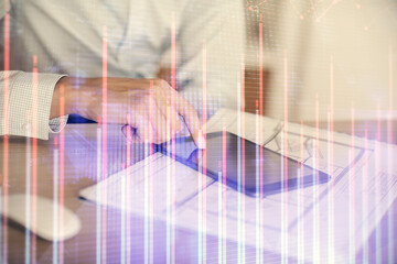 Double exposure of man's hands holding and using a digital device and forex graph drawing. Financial market concept.