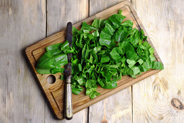 Selective focus. Macro. Fresh chopped spinach on a wooden board. Juicy green spinach