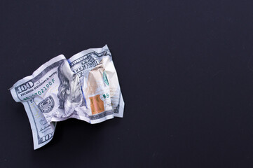 Crumpled one hundred dollar bill on a black background. The concept of the fall of the dollar as a result of the coronovirus pandemic. Copyspace
