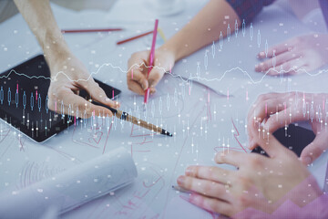 Double exposure of forex graph drawing and man and woman working together holding and using a...