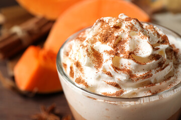 Delicious pumpkin latte with whipped cream on table, closeup