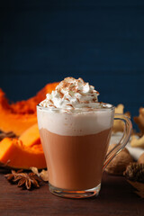 Delicious pumpkin latte and ingredients on brown wooden table, closeup