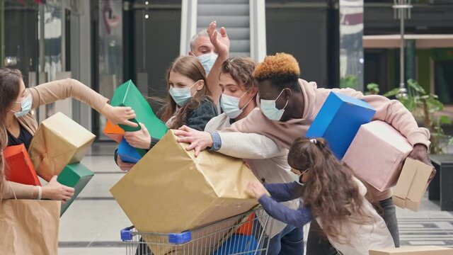Group of Shopaholics With Shopping Bags Wearing Medical Masks to Protect Themselves From Disease. Group of Satisfied Customers are Fighting Paper Bags With Purchases at Mall After Buying Purchases.
