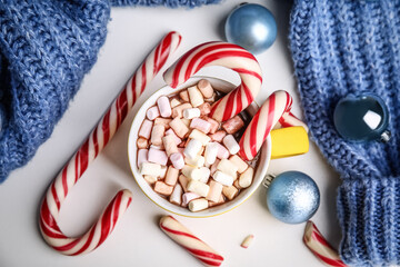 Fototapeta na wymiar Cup of tasty cocoa with marshmallows, candy canes and Christmas balls on white table, flat lay