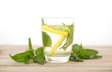 A glass of lemon mint water and fresh mint leaves