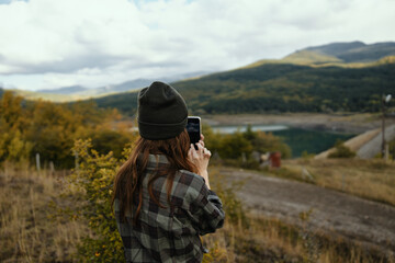 Woman photographs nature in the mountains and a warm hat fresh air in the fall