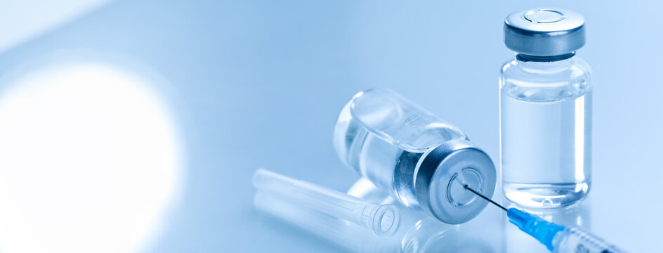 Medical syringe with a needle and a bollte with vaccine.