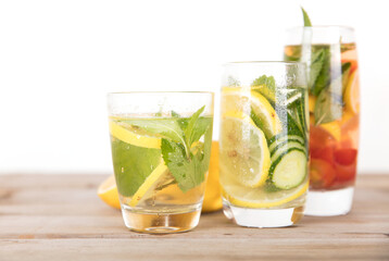 Three glasses of lemon cucumber mint water and freshly cut lemon fruit