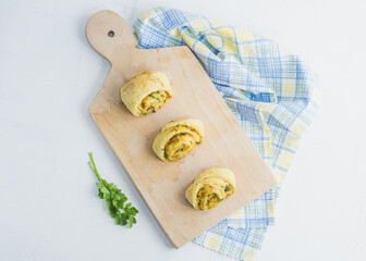 Home made buns with garlic, green parsley and sweet pepper in a napkin and wooden cutting board white background.