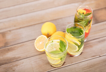 Three glasses of lemon cucumber mint water and freshly cut lemon fruit