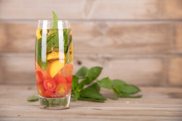 A cup of refreshing lemon mint fruit tea and fresh mint leaves next to the cup