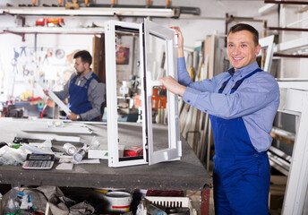 Happy young labours with finished PVC profiles and windows at factory