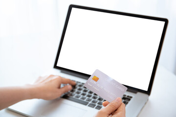 unrecognizable woman holding a credit card in front of the laptop computer screen.