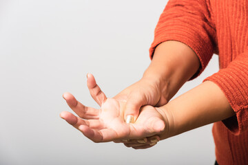 Close up hand of Asian woman she holding her acute pain in wrist of hands, studio shot isolated on...