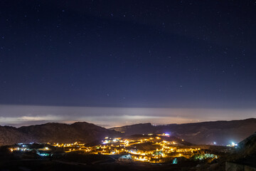 sky full of stars above a town and a mountain range