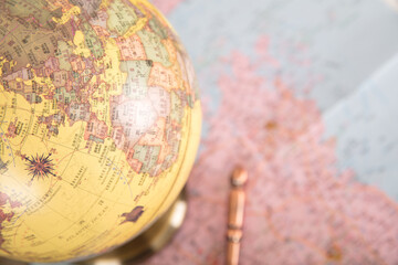 Close-up of a part of the globe and a map and magnifying glass spread out on the bottom table