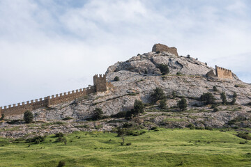 Fototapeta na wymiar The wall that runs along the ridge of the mountain and the towers of Genoese fortress of the 14th century in the Sudak bay on the Peninsula of Crimea