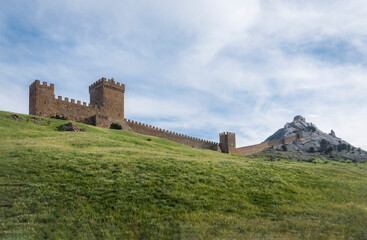 Fototapeta premium The wall that runs along the ridge of the mountain and the towers of Genoese fortress of the 14th century in the Sudak bay on the Peninsula of Crimea