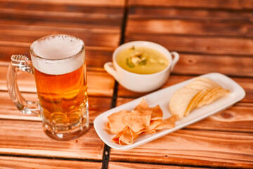 Glass of beer, chips and snacks with guacamole on rustic wooden background. Appetizer with green guacamole with mug or pint of ale. close up, 
