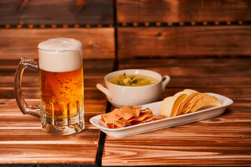 Glass of beer, chips and snacks with guacamole on rustic wooden background. Appetizer with green guacamole with mug or pint of ale. close up, 
