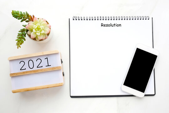 2021 resolution on blank notebook paper, smart phone with blank screen on white marble background, 2021 new year mock up, template, flat lay