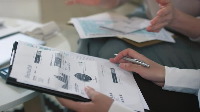 Without face footage of female financial consultant analyzing diagrams and charts of bills and payments explaining details to client