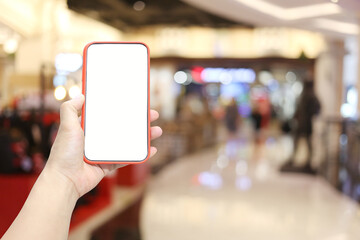 Hand of a man holding smartphone device in the Shopping mall background.