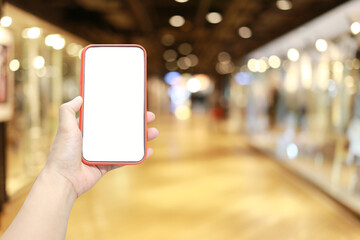 Hand of a man holding smartphone device in the Shopping mall background.