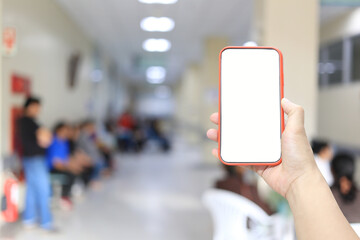 Hand of a man holding smartphone device in the hospital blur background.