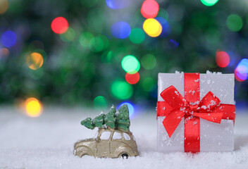 car and christmas gift.

A car and a Christmas present in the snow on the right with colored bokeh and space for text on the left, close-up side view.