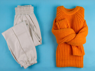 sweater and pants.

Orange sweater and white pants on a blue background, flat lay close-up.