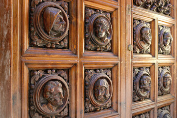 ancient wooden door with engraved ornaments in the wood - portrait heads inside of framed circles and squares