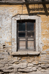 Fototapeta na wymiar Old window on cracked wall with peeling plaster