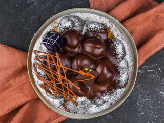 chocolate cake with chocolate.
Chocolate cake with profiteroles and New Year's gift on a gray background with a brown napkin, close-up top view.