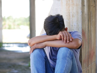 An Indonesian teenager boy worried sitting with a hand on the head. portrait of Asian young man depressed and sad.