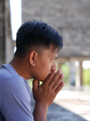An Indonesian teenager boy worried sitting with a hand on the head. portrait of Asian young man depressed and sad.