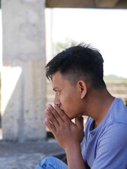 An Indonesian teenager boy worried sitting with a hand on the head. portrait of Asian young man depressed and sad.