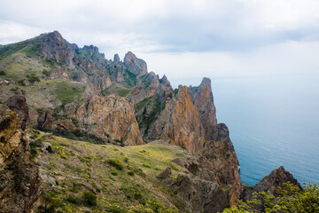 Mountain slope with flowers and peaks of Kara-Dag mountains in the fog of clouds on the Crimean Peninsula