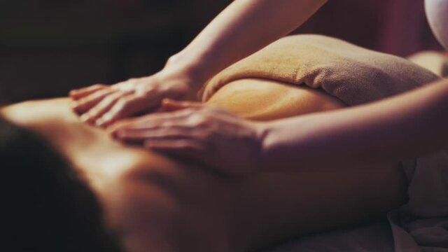 masseur is massaging the girl's back. dim environment. slow motion.