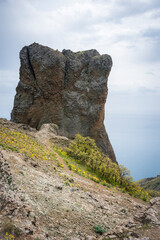 A huge rock of cubic shape on a green mountain valley