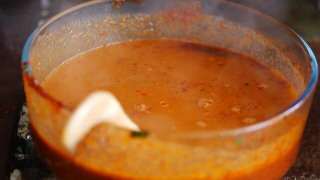 A Indonesian woman watery sambal pecel (peanut sauce) in a glass. Preparing sambal pecal.