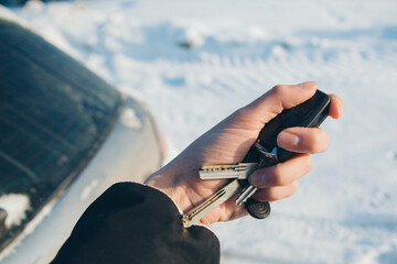 keychain with car keys in hand on the background of snow. trying to start a car in winter
