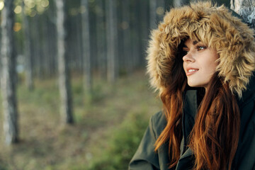 Pretty woman in hooded jacket leaned on a tree outdoors