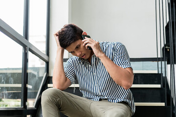 Stressful asian man talking on the phone with serious expression.